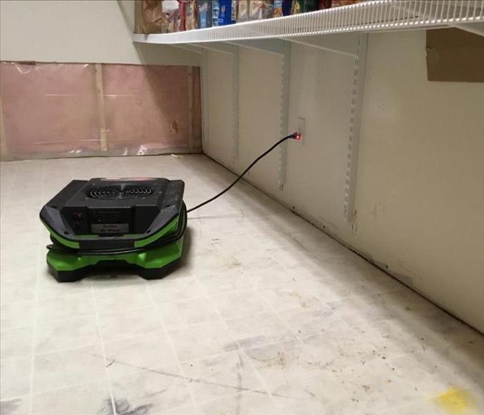 Drying equipment on floor underneath food shelving with back wall partly cut out