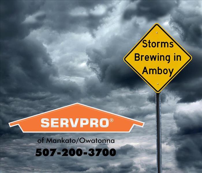 SERVPRO logo and yellow road sign stating "Storms Brewing in Amboy" in front of a dark and cloudy sky.